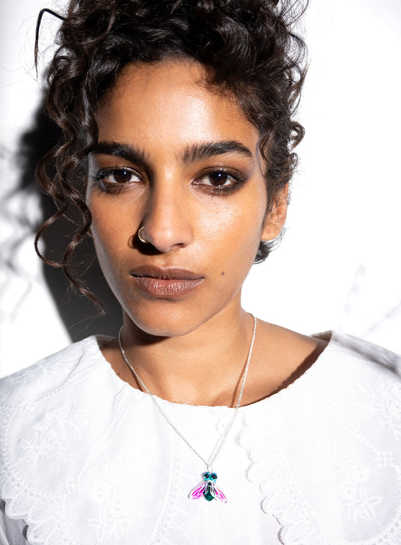 Greenbottle Fly Pendant with Iridescent Wings worn on a white blouse with collars
