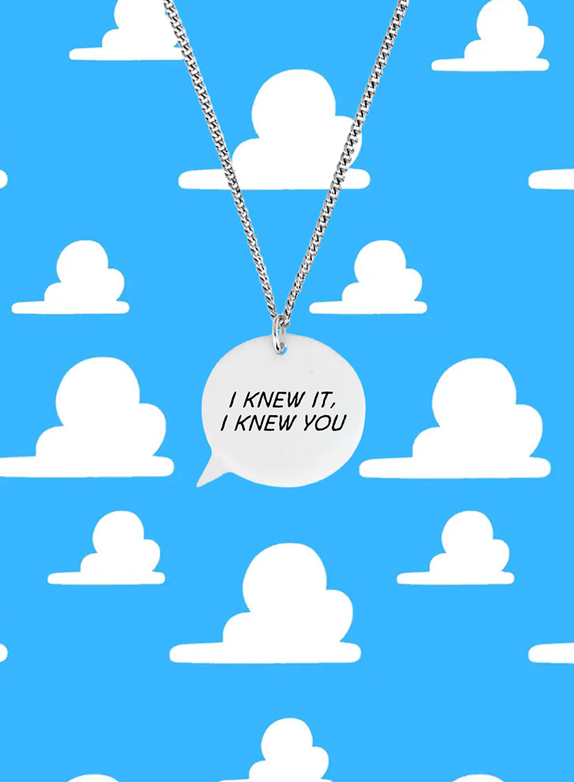 Necklace with a speech bubble pendant on a blue background with white cloud shapes. Necklace reads: I knew it, I knew you.