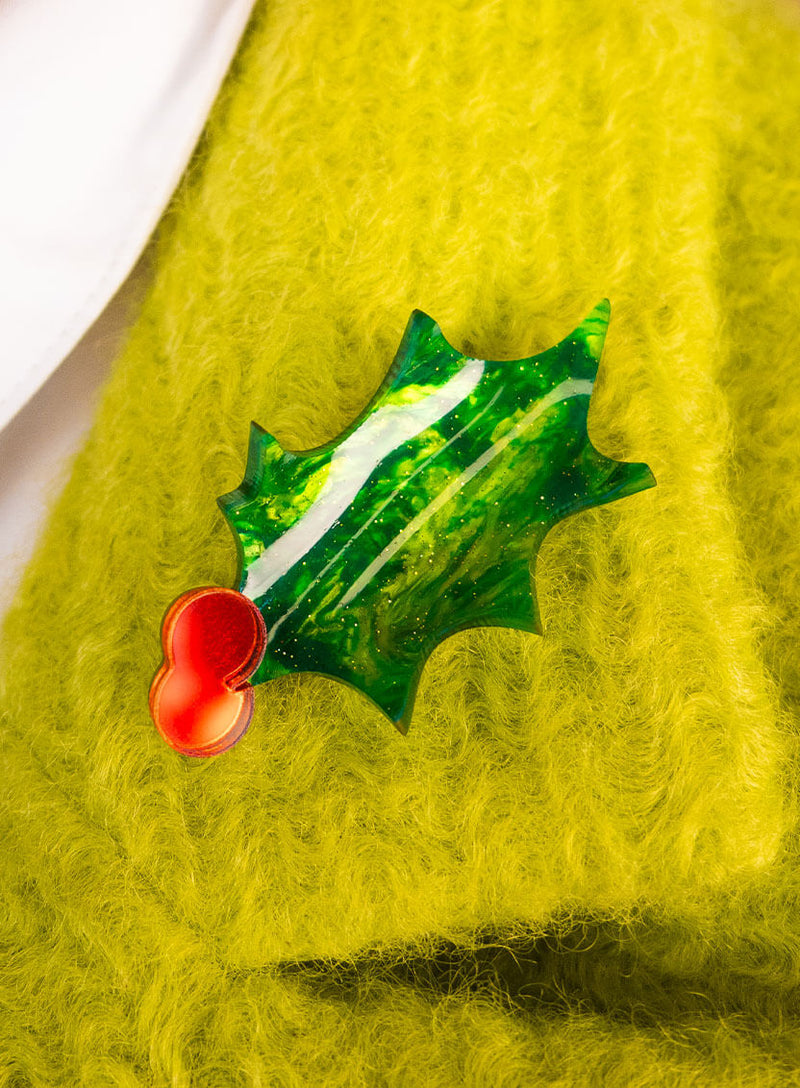 Curved Holly Brooch made from glitter-flecked acrylic worn on a green coat