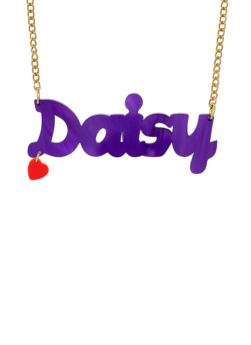A Name necklace in limited edition plum pearl spelling 'Daisy' on a gold chain, with a small red heart charm hanging from the left side, shown against a plain white background.